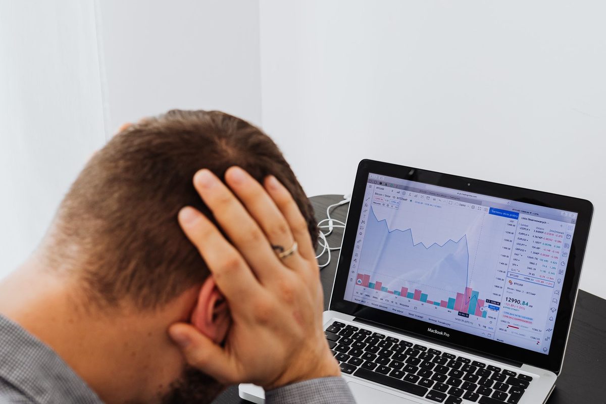 A writer holding his head in frustration while looking at charts on a laptop